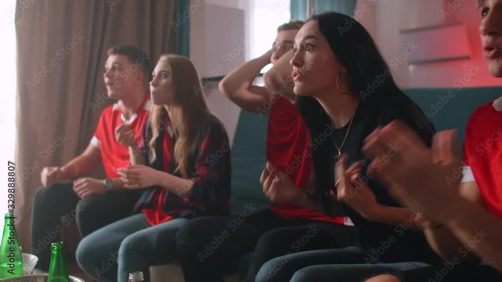 Two female and three male friends watch football on TV at home. Their favourite team wins, company is happy, shouts and hugs all together. Two female and three male friends watch football on TV at home. Their favourite team wins, company is happy, shouts and hugs all together.
