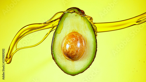 Fresh cut avocado with oil stream. Concept of healthy fruit also useful in cosmetics. photo