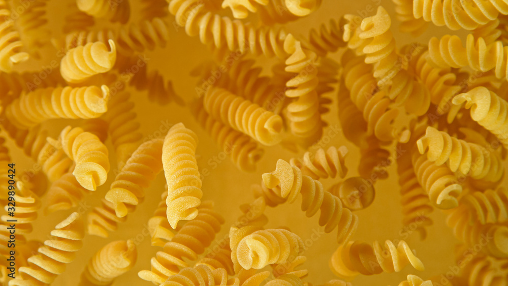Freeze motion of flying uncooked italian pasta fusilli on golden background. Freeze motion of flying uncooked italian pasta fusilli on golden background.