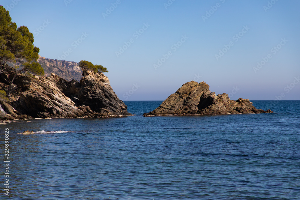 Catalan sea coast rocks in a calm sea with blue sky as background and copy space