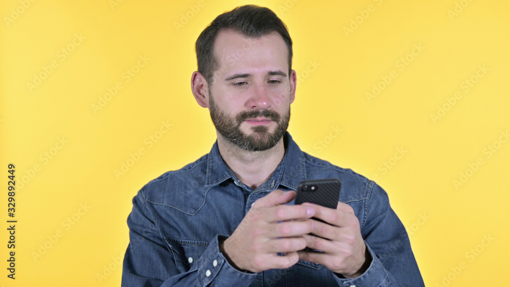 Portrait of Young Man using Smartphone, Yellow Background Portrait of Young Man using Smartphone, Yellow Background