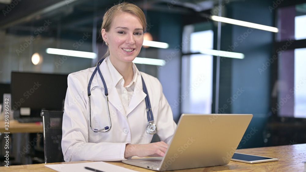 Cheerful Young Female Doctor Working on Laptop in Office Cheerful Young Female Doctor Working on Laptop in Office