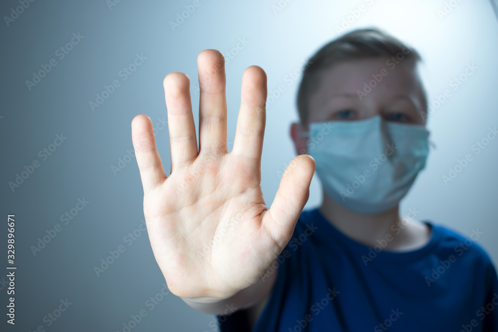 The child shows a hand with a stop. A child in an antiviral mask. The child shows a hand with a stop. A child in an antiviral mask.
