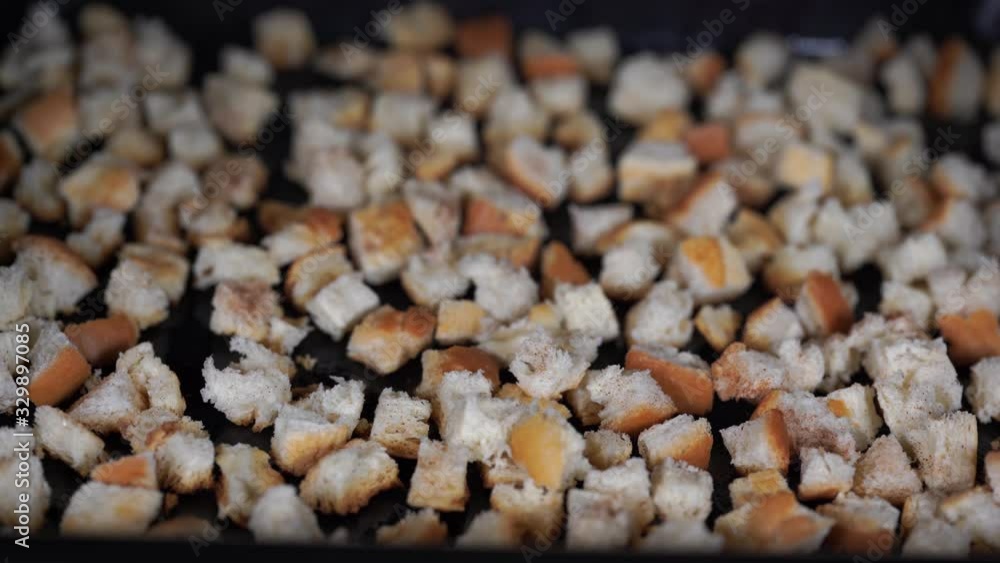 Crackers or rusks made from homemade white bread are baked in the oven in close-up. Cooking croutons. The texture of the slices of dry rye bread. Crackers or rusks made from homemade white bread are baked in the oven in close-up. Cooking croutons. The texture of the slices of dry rye bread.