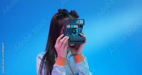 Stylish incognito female using retro Polaroid camera.