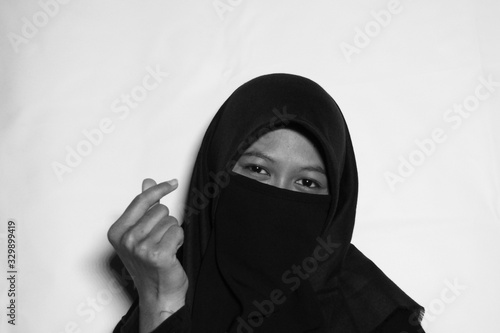 Close up view of Pretty lady woman girl wear hijab jilbab niqab kerudung niqaab scarf cover face and only show visible look of her beauty eyes. Fit for put design life image. Black white with grain t