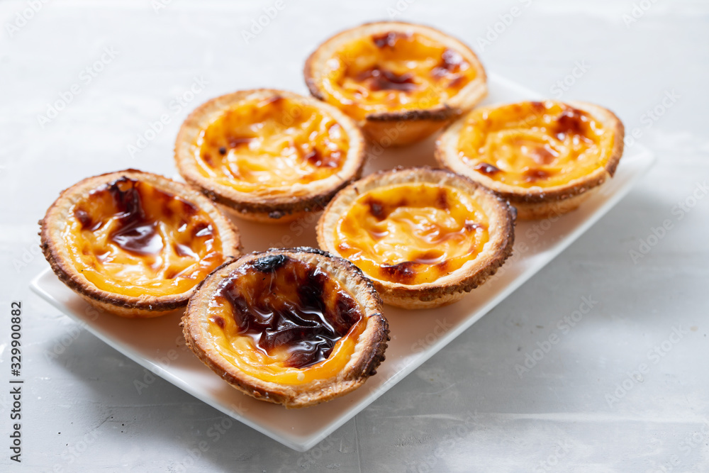 typical portuguese sweets pastel de nata on white dish on ceramic background
