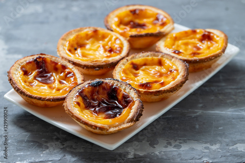 typical portuguese sweets pastel de nata on white dish on ceramic background