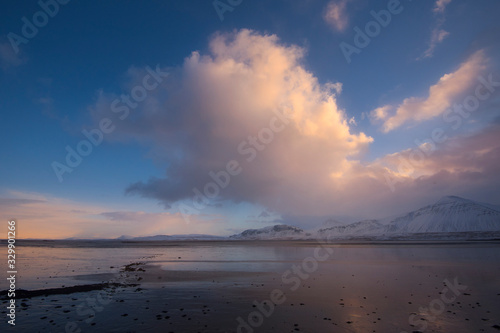 Dark clouds developing in the middle of winter over the frozen Iceland coast at sunset