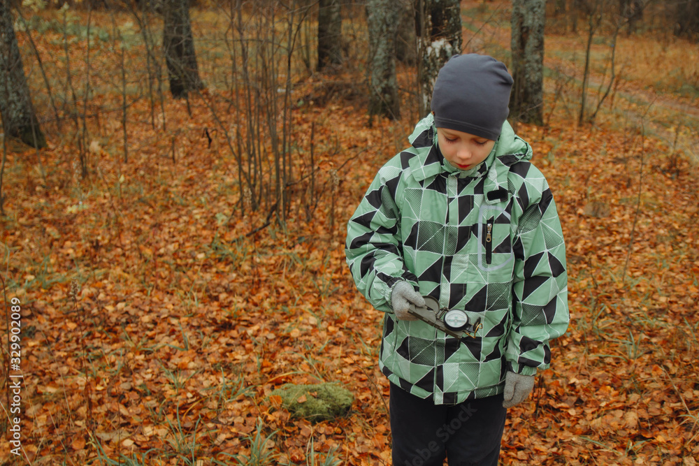A teenage boy is guided by a compass in the woods. It's raining. Autumn. A teenage boy is guided by a compass in the woods. It's raining. Autumn.