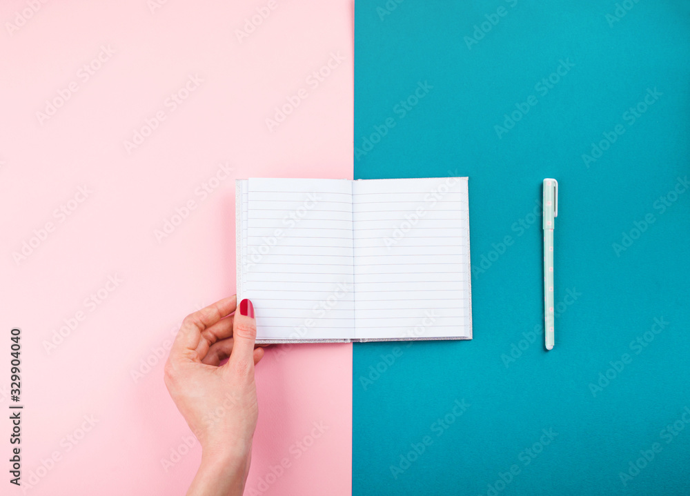 Duotone pink and blue background with open notepad in female hand and pen. Diary, planning, studying concept Duotone pink and blue background with open notepad in female hand and pen. Diary, planning, studying concept