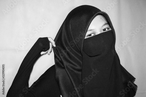 Close up view of Pretty lady woman girl wear hijab jilbab niqab kerudung niqaab scarf cover face and only show visible look of her beauty eyes. Fit for put design life image. Black white grain texture photo