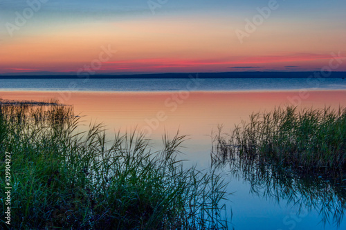 Beautiful pink sunset on the lake. Water, sky, coast, horizon.