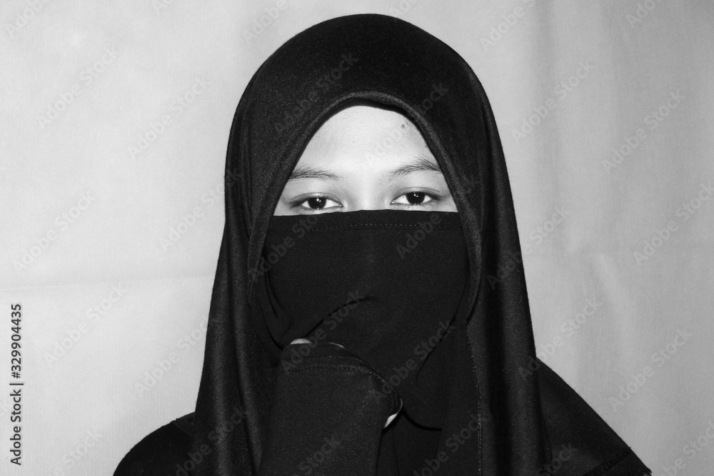 Close up view of Pretty lady woman girl wear hijab jilbab niqab kerudung niqaab scarf cover face and only show visible look of her beauty eyes. Fit for put design life image. Black white grain texture Close up view of Pretty lady woman girl wear hijab jilbab niqab kerudung niqaab scarf cover face and only show visible look of her beauty eyes. Fit for put design life image. Black white grain texture