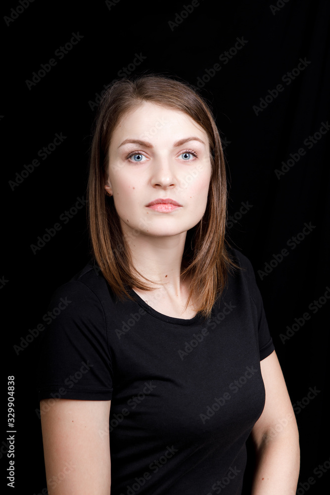Young woman in a black t-shirt looking directly at the camera on black background Young woman in a black t-shirt looking directly at the camera on black background
