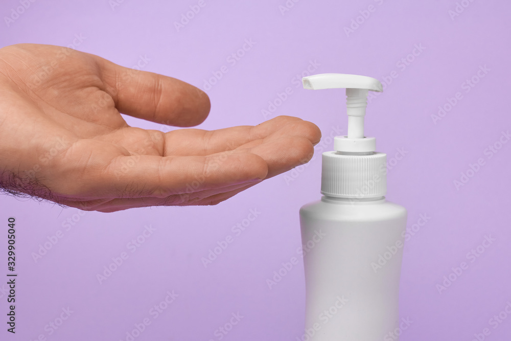 Closeup mans hand using antibacterial liquid soap to protect against COVID-19. Man uses gel for cleaning hands on a blue background. Closeup mans hand using antibacterial liquid soap to protect against COVID-19. Man uses gel for cleaning hands on a blue background.