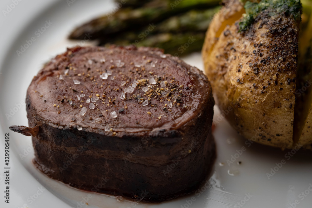 bacon wrapped tenderloin steak on white plate bacon wrapped tenderloin steak on white plate