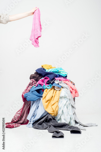 hand throws clothes into a pile with used clothes. Pile of used clothes on a light background. Second hand for recycling