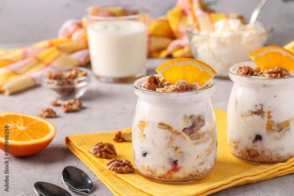 Granola crispy honey muesli with natural yogurt, frozen berries, oranges and nuts in glass jars on a gray background, healthy food Granola crispy honey muesli with natural yogurt, frozen berries, oranges and nuts in glass jars on a gray background, healthy food