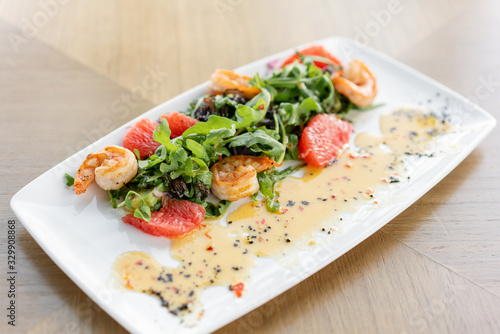 Fresh salad with grilled shrimps, slice grapefruit and arugula salad and spicy fried prawns. Restaurant menu, natural and organic food concept.