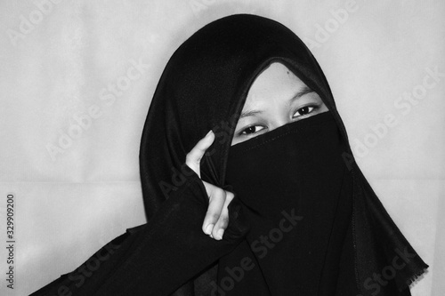 Close up view of Pretty lady woman girl wear hijab jilbab niqab kerudung niqaab scarf cover face and only show visible look of her beauty eyes. Fit for put design life image. Black white  with grain t photo