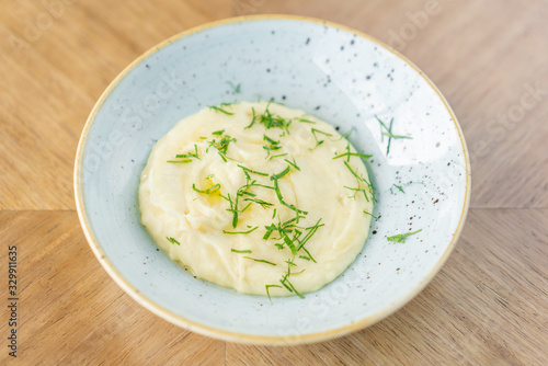 Mashed potatoes with dill in plate on a wooden background