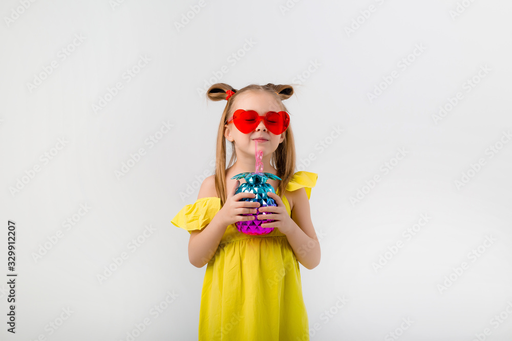 happy child girl in sunglasses holding a glass with a cocktail on a white background isolate