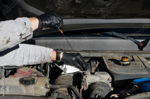 Close up of man's hands wearing latex gloves for checking the oil dipstick during a DIY at home oil change