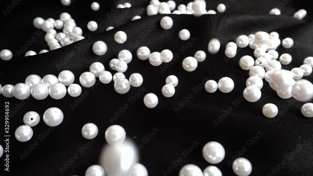 White pearls fall on black fabric. Slow motion. White pearls fall on black fabric. Slow motion.