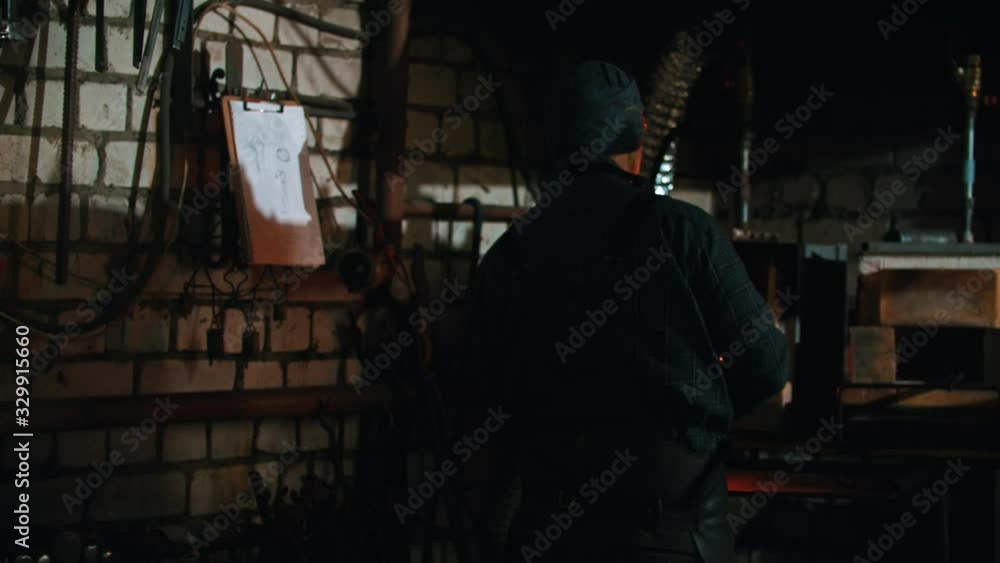Forging industry - a man blacksmith holding a hot piece of metal Forging industry - a man blacksmith holding a hot piece of metal