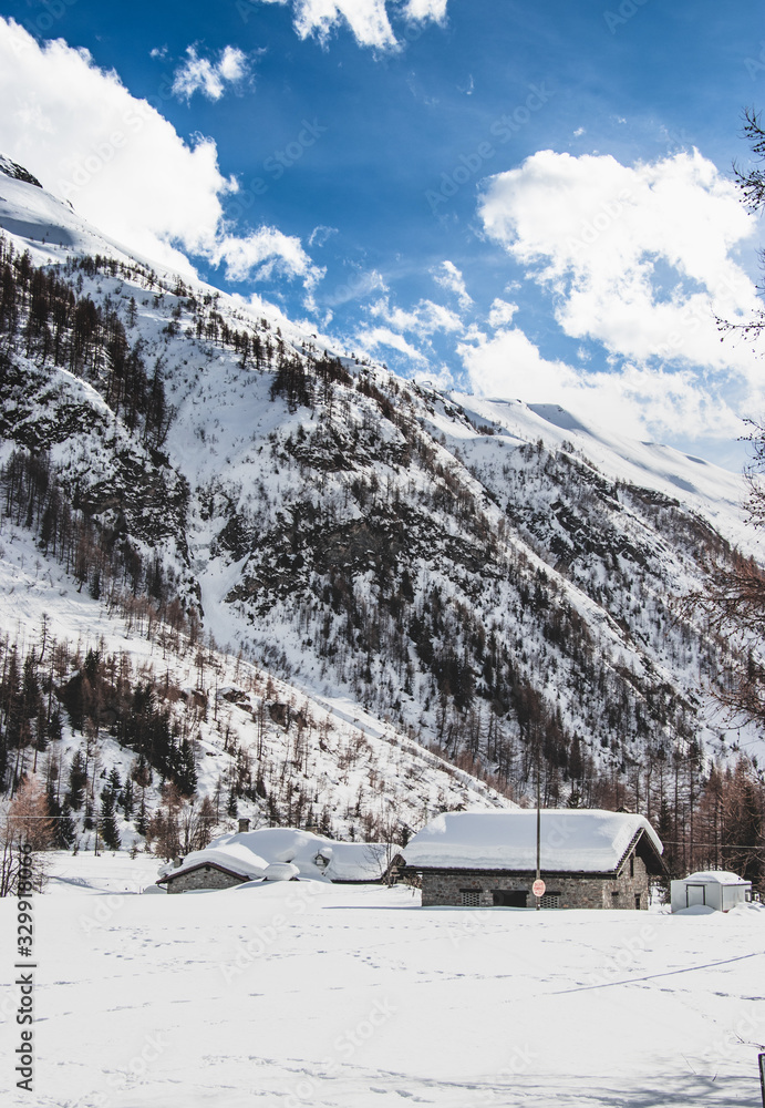 Isolated house with snow on the roof in a snowy alpine valley