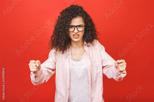 Disappointed caucasian brunette woman, looking agressive isolated on red background in studio. People emotions, lifestyle concept. photo