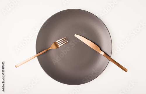 Fork and knife on a empty grey plate on white background