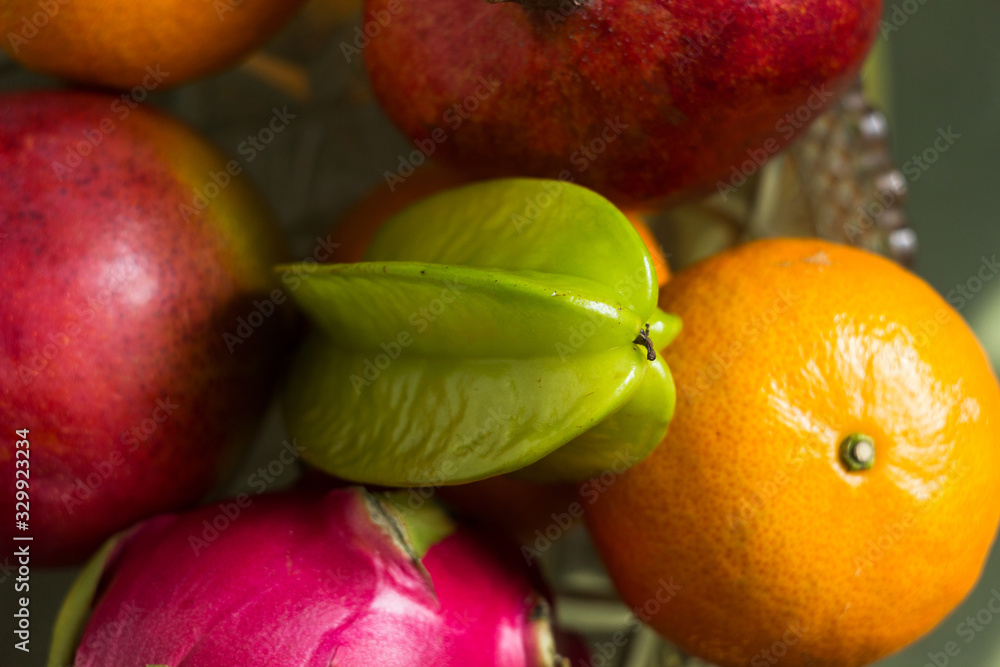 A lot of tropical fruits in a glass vase. Exotic fruits: averrhoa carambola, Pitahaya, Mango, tangerines, pomegranate fruit A lot of tropical fruits in a glass vase. Exotic fruits: averrhoa carambola, Pitahaya, Mango, tangerines, pomegranate fruit