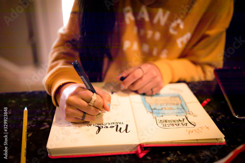 Closeup of young teen girl writing in bullet journal on mood tracker page