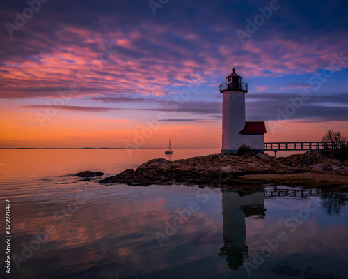 Sunset reflections at Annisquam Lighthouse with sail boat - Gloucester, Massachusetts.