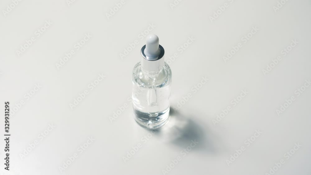 Cosmetic Pipette in Transparent Glass Bottle Mock Up. Close Up of Serum Skin Care Gel on White Background with Shadows Effect. 4k Footage. Cosmetic Pipette in Transparent Glass Bottle Mock Up. Close Up of Serum Skin Care Gel on White Background with Shadows Effect. 4k Footage.