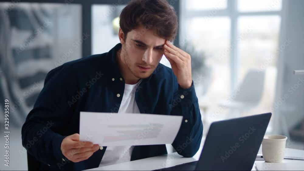 Focused business man reading documents. Serious guy checking data in papers
