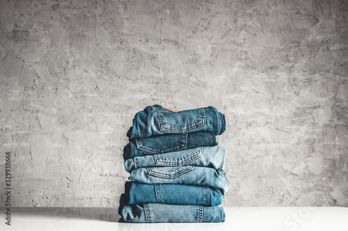 Stack of blue jeans on a gray background