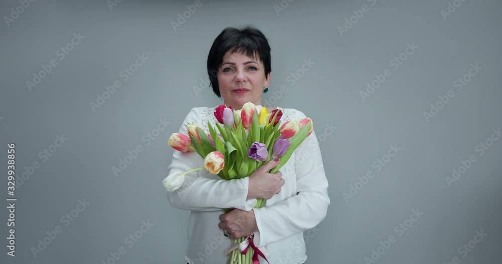 Woman with gifts. Attractive woman holds bouquet of flowers tulips in her hands gift soft toy looking at camera and smiling. Woman with gifts. Attractive woman holds bouquet of flowers tulips in her hands gift soft toy looking at camera and smiling.
