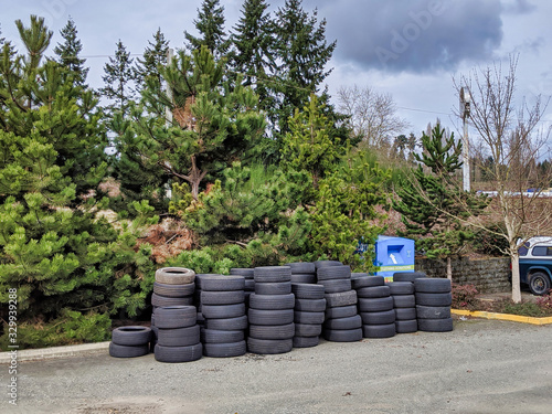 Street view of a large pile of tires outside of a car repair shop
