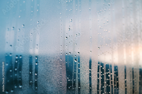 Raindrops on window with blurry snow covered mountain view at evening with copy space