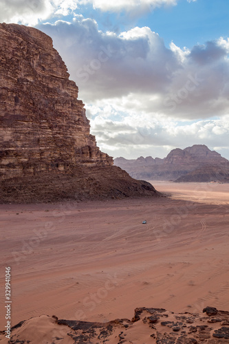 Kingdom of Jordan  Wadi Rum desert  sunny winter day scenery landscape with white puffy clouds and warm colors. Lovely travel photography. Beautiful desert could be explored on safari. Miniature car