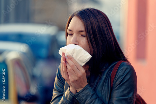 Tela Ill woman with flu virus caughing sneezing in handkerchief  outdoors