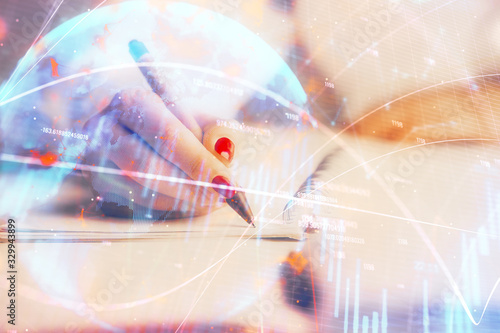 Double exposure of woman's hands making notes with forex graph hologram. Concept stock market analysis.