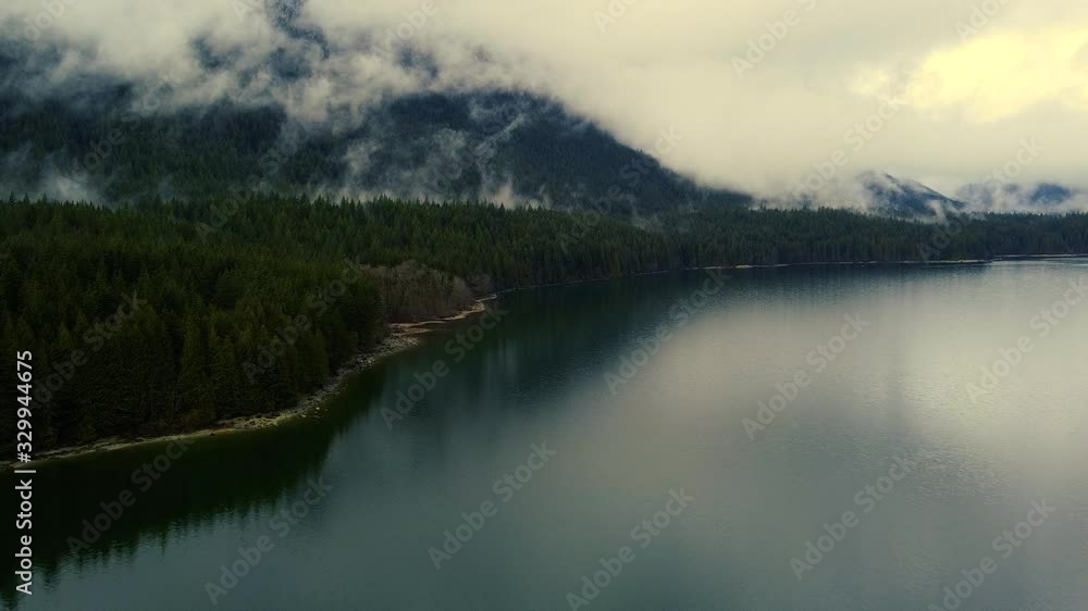 Aerial view of the foggy mountains, green pine forest and the lake reflecting sky Aerial view of the foggy mountains, green pine forest and the lake reflecting sky
