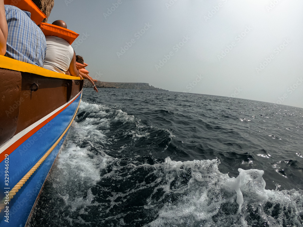 Obraz premium Residents and tourists visit the coast of Malta in a tourist boat, protected with life jackets. Theme park.