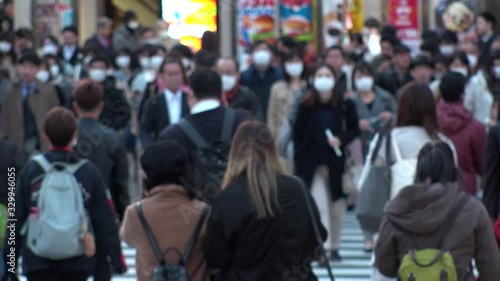 TOKYO, JAPAN - MARCH 2020 : Crowd of people at the street near Shinjuku station in rush hour. Commuters and tourists wearing surgical mask to protect from Coronavirus(COVID-19) or cold. Slow motion.