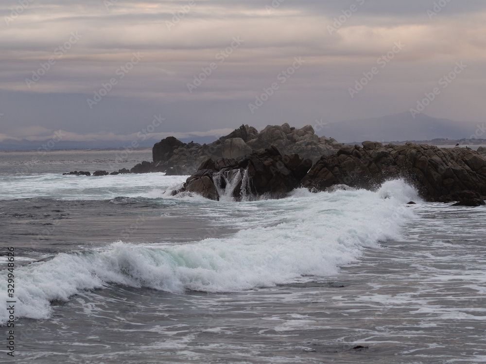 Waves of the Pacific Ocean collide with the rocks of the coast in Monterrey. California.