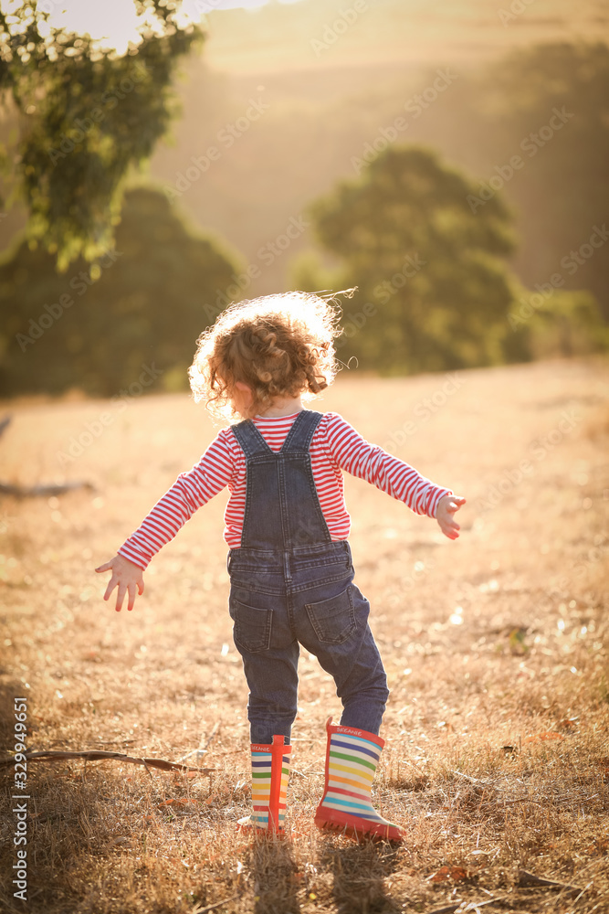 Fototapeta premium Cute little girl wearing overalls and gumboots
